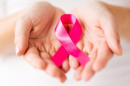 close up of hands and pink cancer awareness ribbon