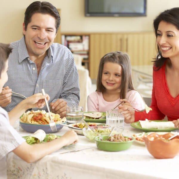 Young Hispanic Family Enjoying Meal At Home