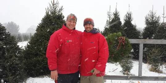 two men in red coats with fir trees