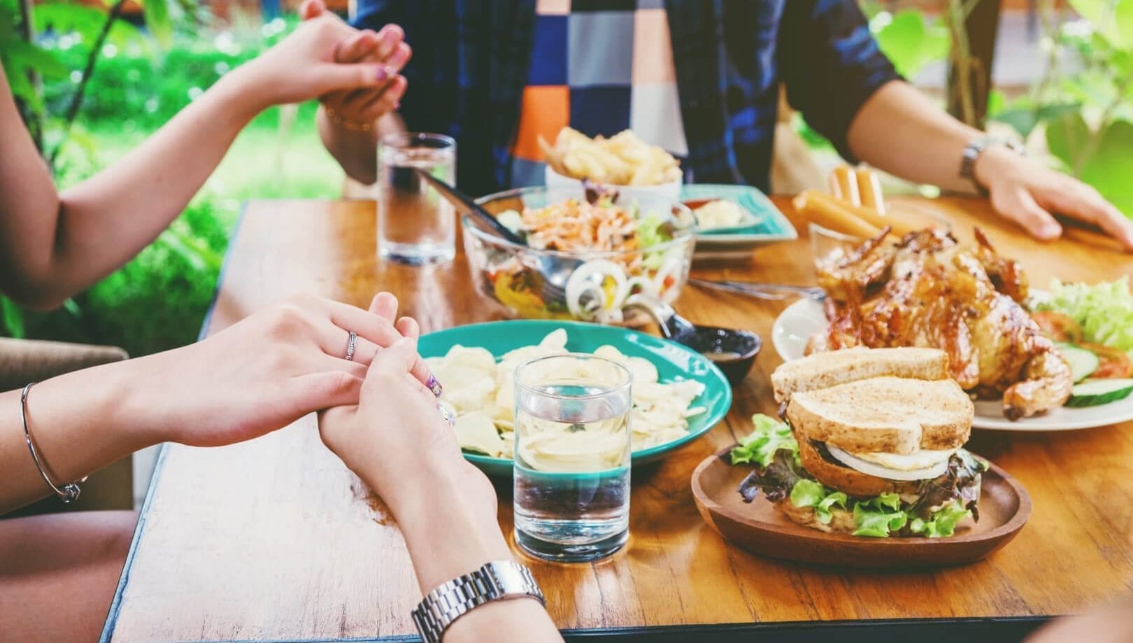 Friends Saying Grace at Dinner Table