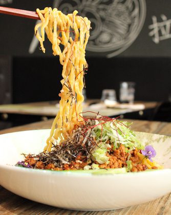 Noodles hanging from chopsticks